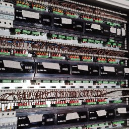 Smart Home Leszno - Inteligentny Dom IGVEL - Głogów, Rawicz, Gostyń, Kościan, Śrem - Rozdzielnia elektryczna z modułami M-REL-10s Ampero, bezpiecznikami Hager i licznymi przewodami. Widoczne złączki, kable w listwach i oznaczenia.