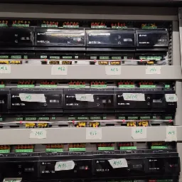 Rozdzielnia elektryczna z modułami sterującymi Ampio M-REL-10s i M-INOC-8s, widoczne bezpieczniki i okablowanie, etykiety M1-M14. Instalacja inteligentnego domu.