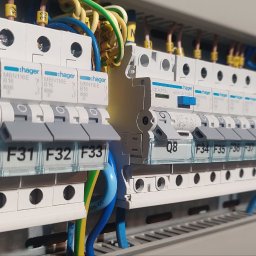 Smart Home Leszno - Inteligentny Dom IGVEL - Głogów, Rawicz, Gostyń, Kościan, Śrem - Rozdzielnia elektryczna marki Hager. Widoczne zainstalowane bezpieczniki z opisami Q7, Q8, F31, F32, F33, F34, F35. Kabelki w kolorach: niebieski, żółty, zielony.