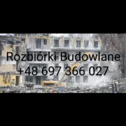 Ciężki sprzęt CAT 310 na tle budynku w trakcie rozbiórki, widoczne gruzy i tumany kurzu.