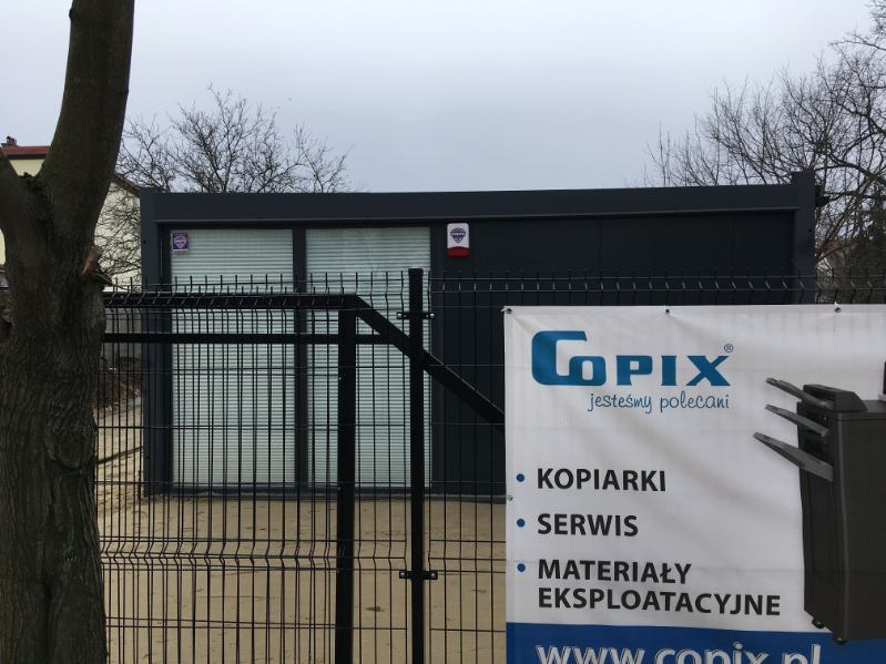 Budynek firmy Copix z banerem reklamowym oferującym kserokopiarki, serwis i materiały eksploatacyjne, widoczny przez czarny metalowy płot.