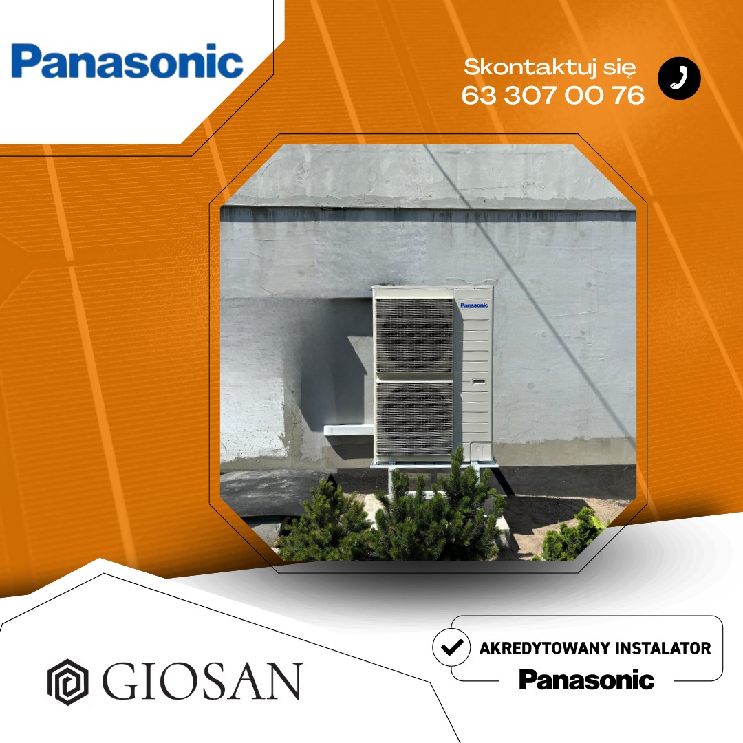 Zewnętrzna jednostka klimatyzacji Panasonic zamontowana na szarej ścianie budynku, widoczne małe iglaki u podstawy.