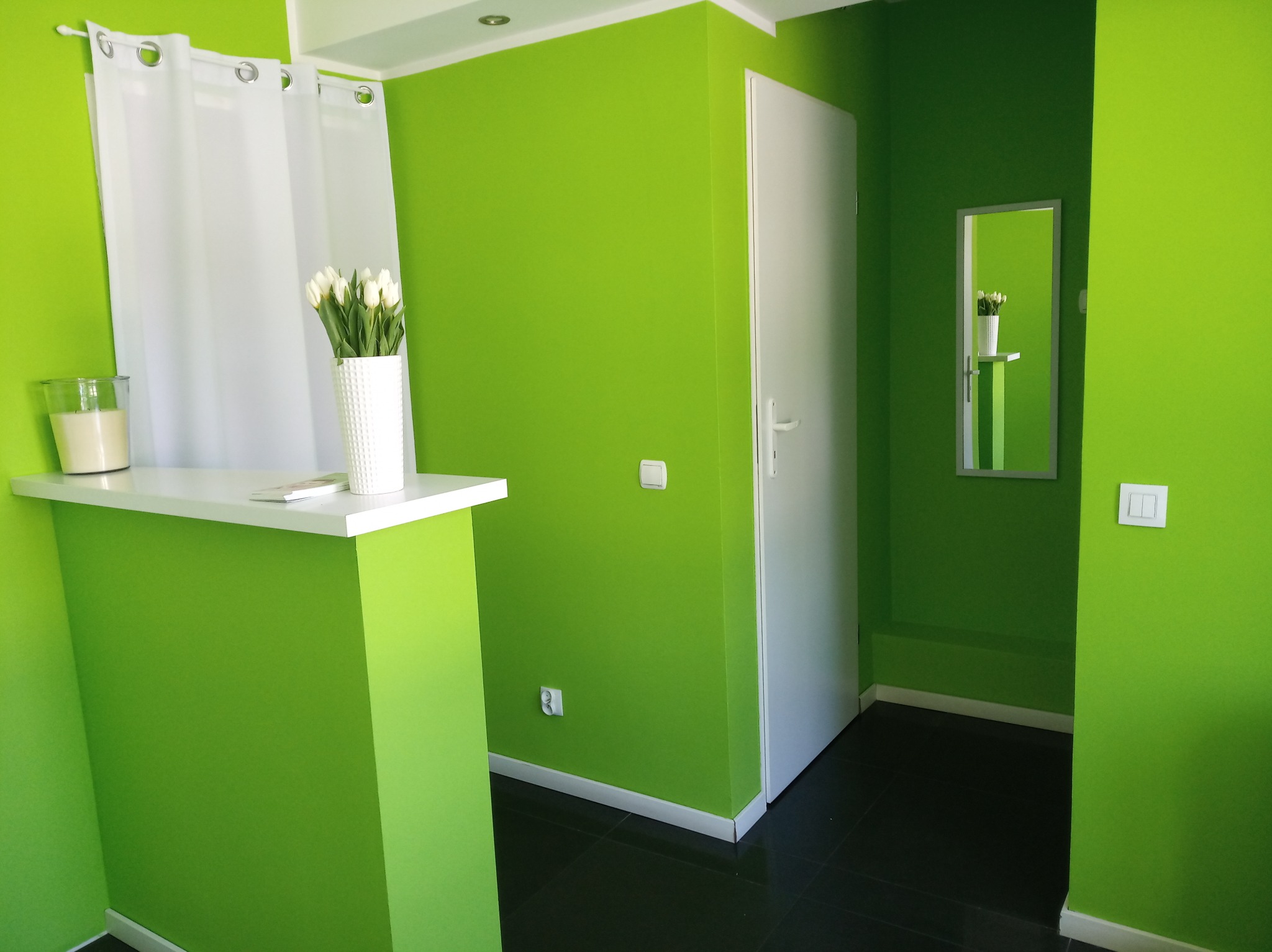 Jasnozielone wnętrze gabinetu w Tarnowskich Górach z recepcją, białymi tulipanami w wazonie i minimalistycznym wystrojem.