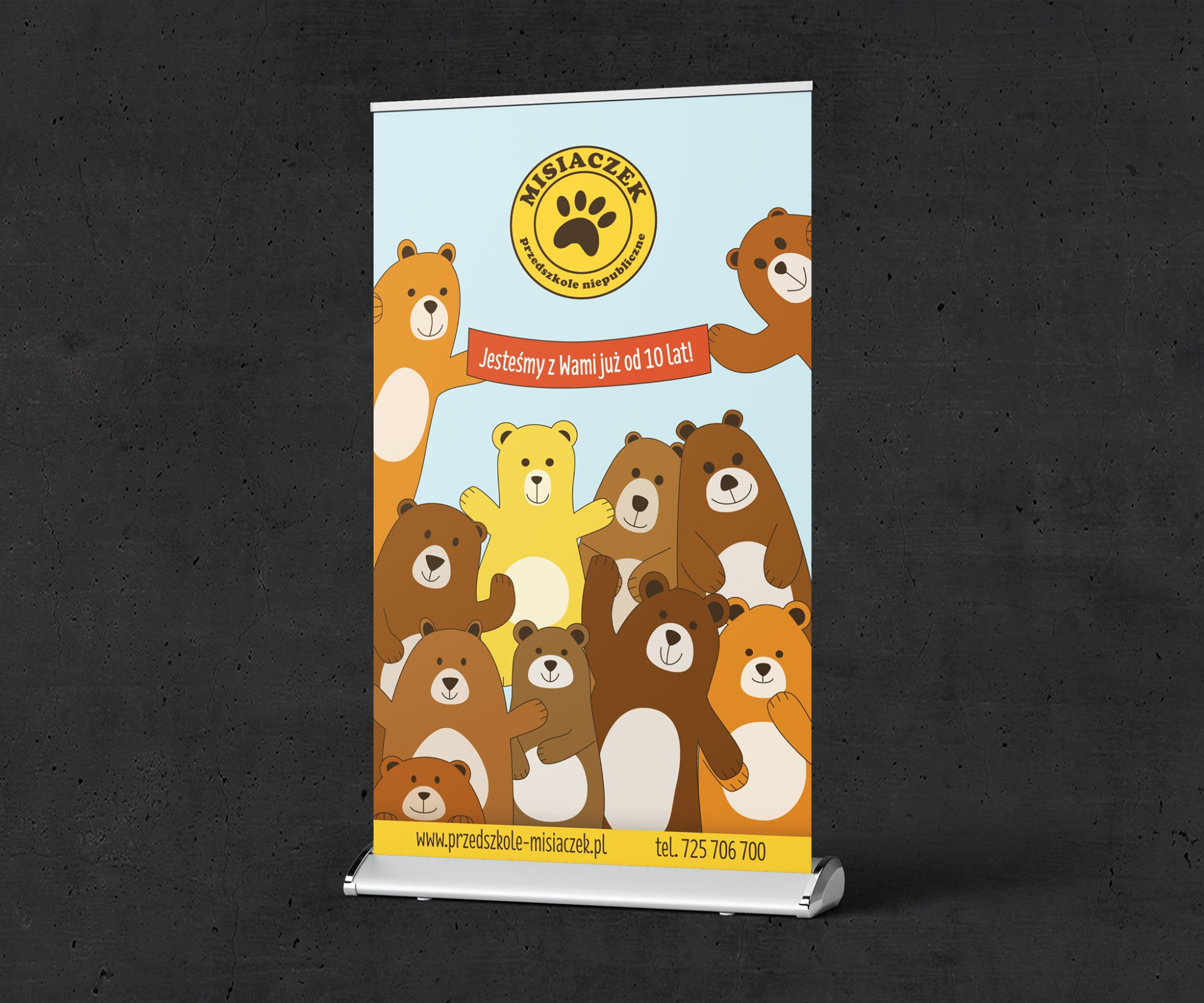 Rollup reklamowy z ilustracjami misiów dla przedszkola 'Misiaczek', informujący o 10 latach działalności, z adresem strony internetowej i numerem telefonu.