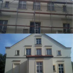 Dwukondygnacyjny dom z jasną elewacją, górna część w trakcie prac elewacyjnych, widoczne rusztowania i drabina, dolna część po remoncie, z widocznym fragmentem zaparkowanego samochodu.