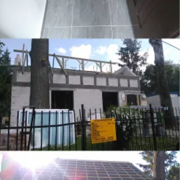 Budowa domu w Bartoszycach w trakcie realizacji: widok na ściany z betonu komórkowego, drewnianą konstrukcję dachu oraz okno wystawowe oparte o ogrodzenie.