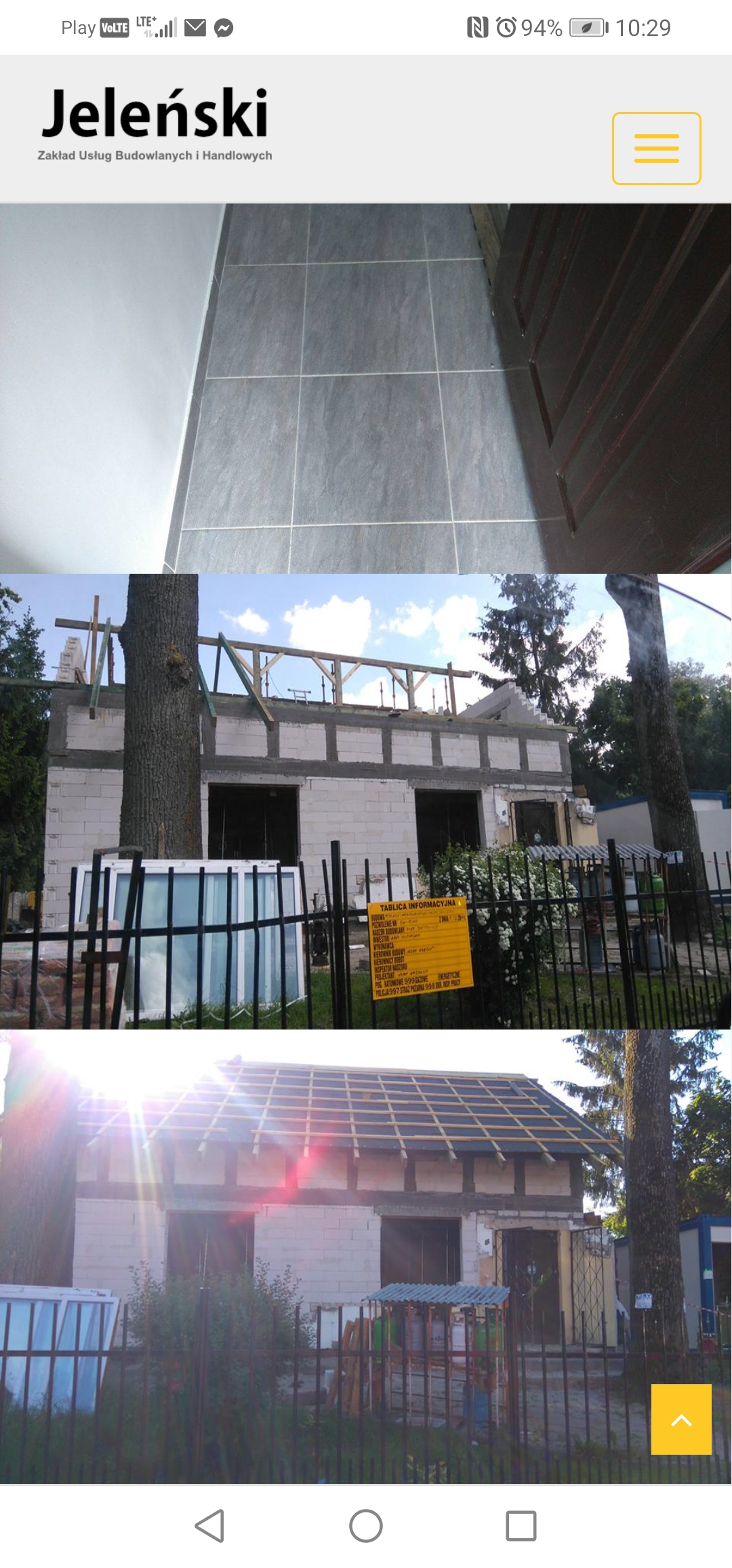 Budowa domu w Bartoszycach w trakcie realizacji: widok na ściany z betonu komórkowego, drewnianą konstrukcję dachu oraz okno wystawowe oparte o ogrodzenie.