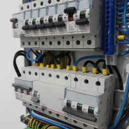 Rozdzielnica elektryczna z zainstalowanymi bezpiecznikami i przewodami. Widoczne przewody w różnych kolorach oraz listwy zaciskowe. Bezpieczniki marki Legrand.