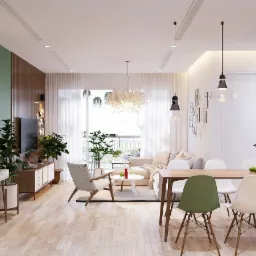 Jasne, przestronne wnętrze mieszkania z drewnianą podłogą, zieloną ścianą z dekoracyjnymi talerzami, stołem jadalnym z krzesłami, roślinami doniczkowymi i sofą w tle.