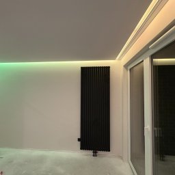 I-TECH - Nowoczesne wnętrze z czarnym grzejnikiem panelowym, oświetleniem LED RGB w suficie i dużym oknem balkonowym. Minimalistyczny design, surowy beton na podłodze.
