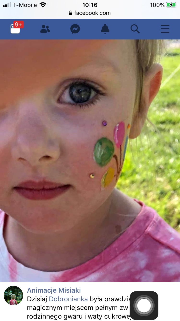 Portret dziewczynki z pomalowaną twarzą w kolorowe balony i brokatowe kropki, wykonany w plenerze.