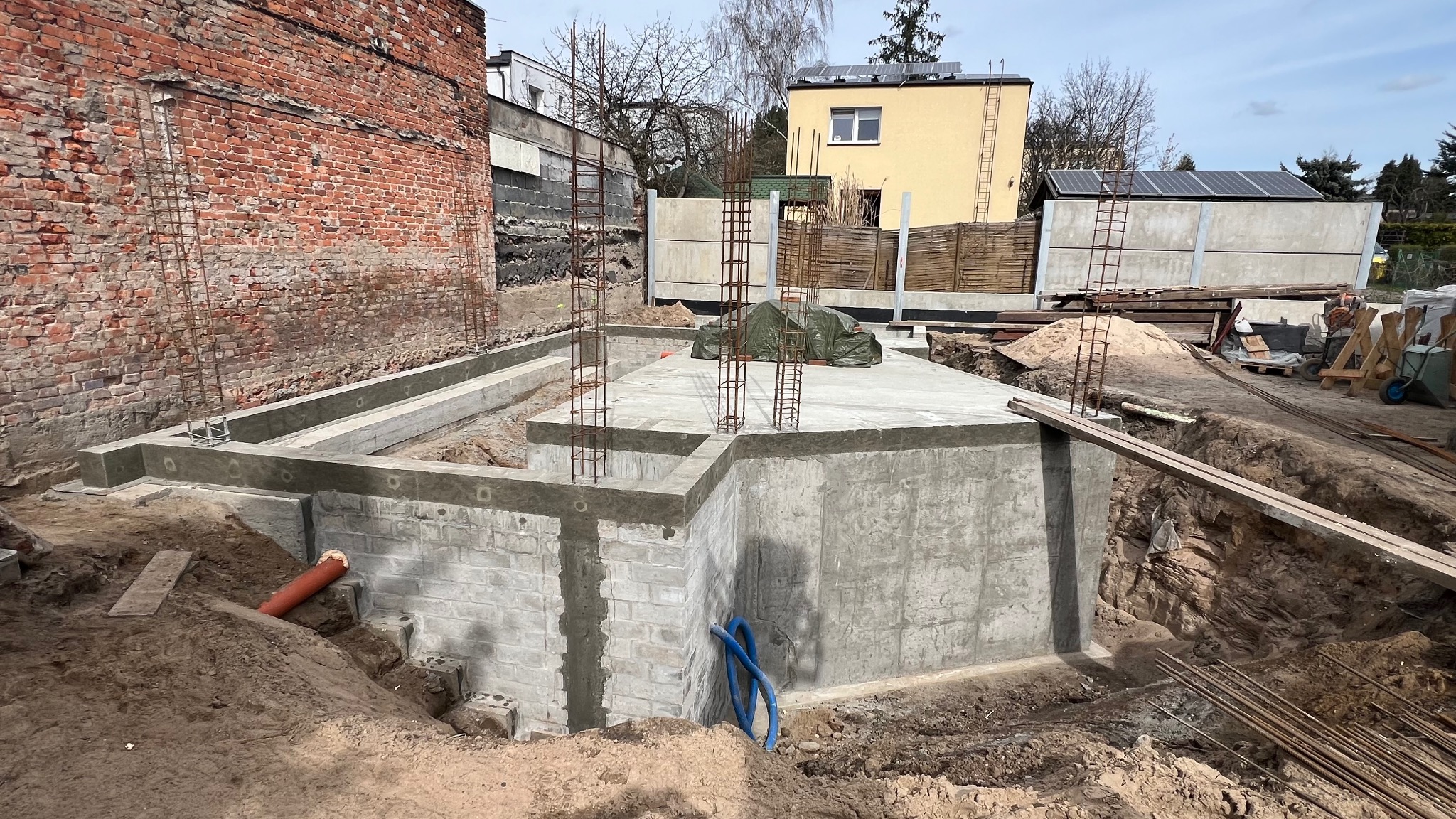 Fundamenty domu jednorodzinnego zbrojone stalą, widoczne ściany fundamentowe z bloczków betonowych. Prace budowlane w Bydgoszczy, etap wylewania płyty fundamentowej.