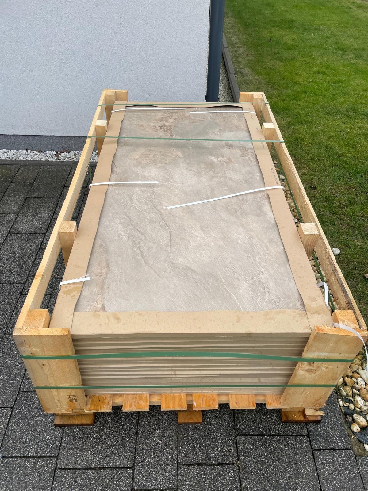 Paleta z płytami kamiennymi na taras, zabezpieczona drewnianą ramą i pasami, gotowa do montażu. Widok z góry.