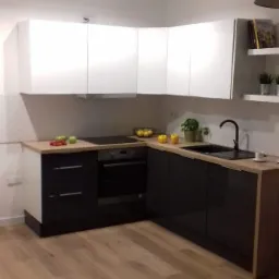 Nowoczesna kuchnia w odcieniach bieli i czerni z drewnianym blatem, oświetlona trzema punktowymi lampami sufitowymi, z owocami na blacie i książkami na półce.