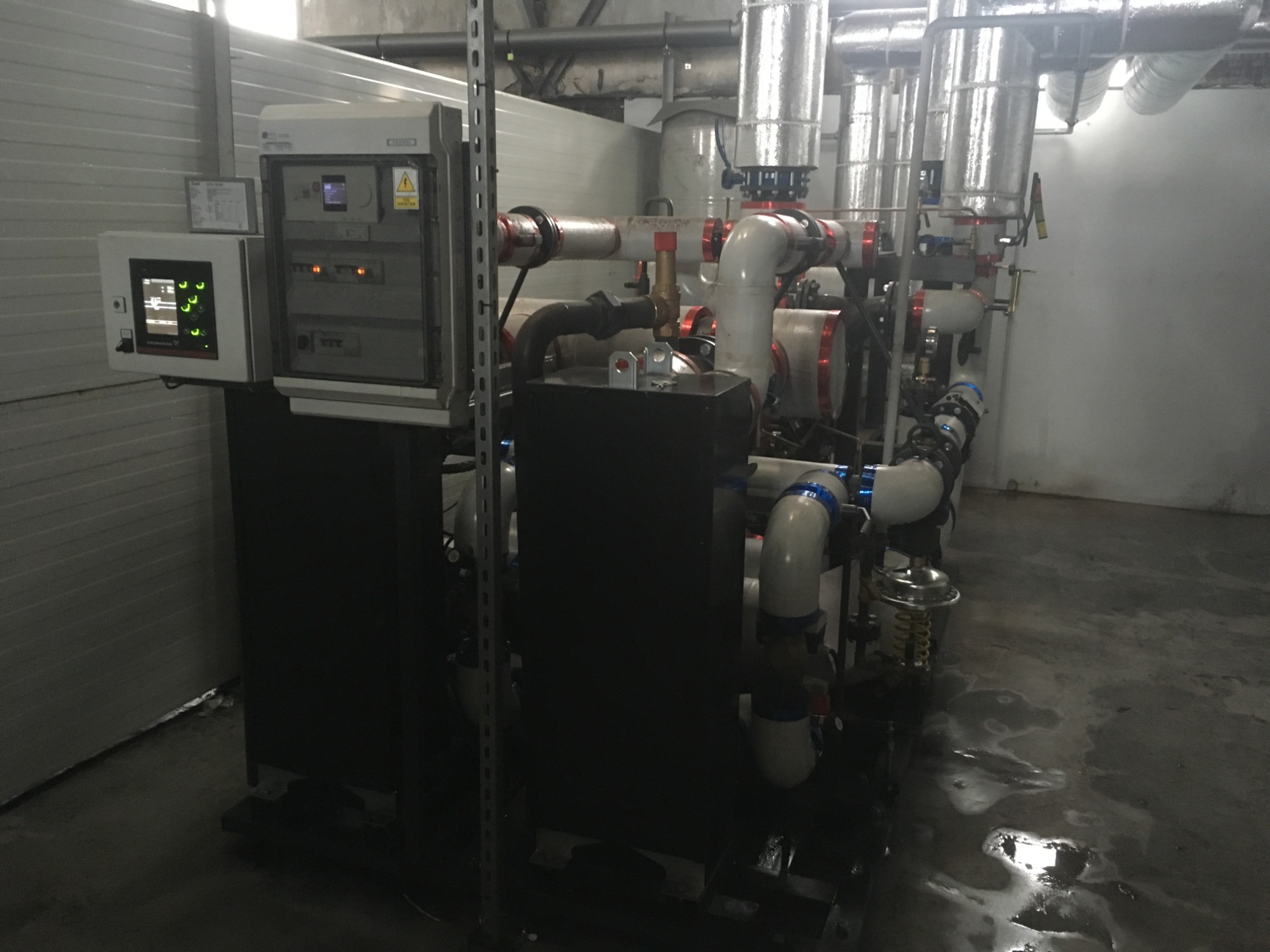 Stacja wymiennikowa z rurami i elementami sterującymi, zainstalowana w zakładzie ICHEMAD-PROFARB w Gliwicach, widoczne panele kontrolne i izolowane rury.