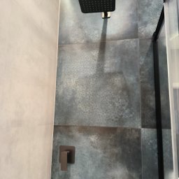 BestBud - Nowoczesna kabina prysznicowa z deszczownicą i szarymi płytkami w geometryczny wzór. Widoczny panel sterujący i fragment półki na kosmetyki. Minimalistyczny design.