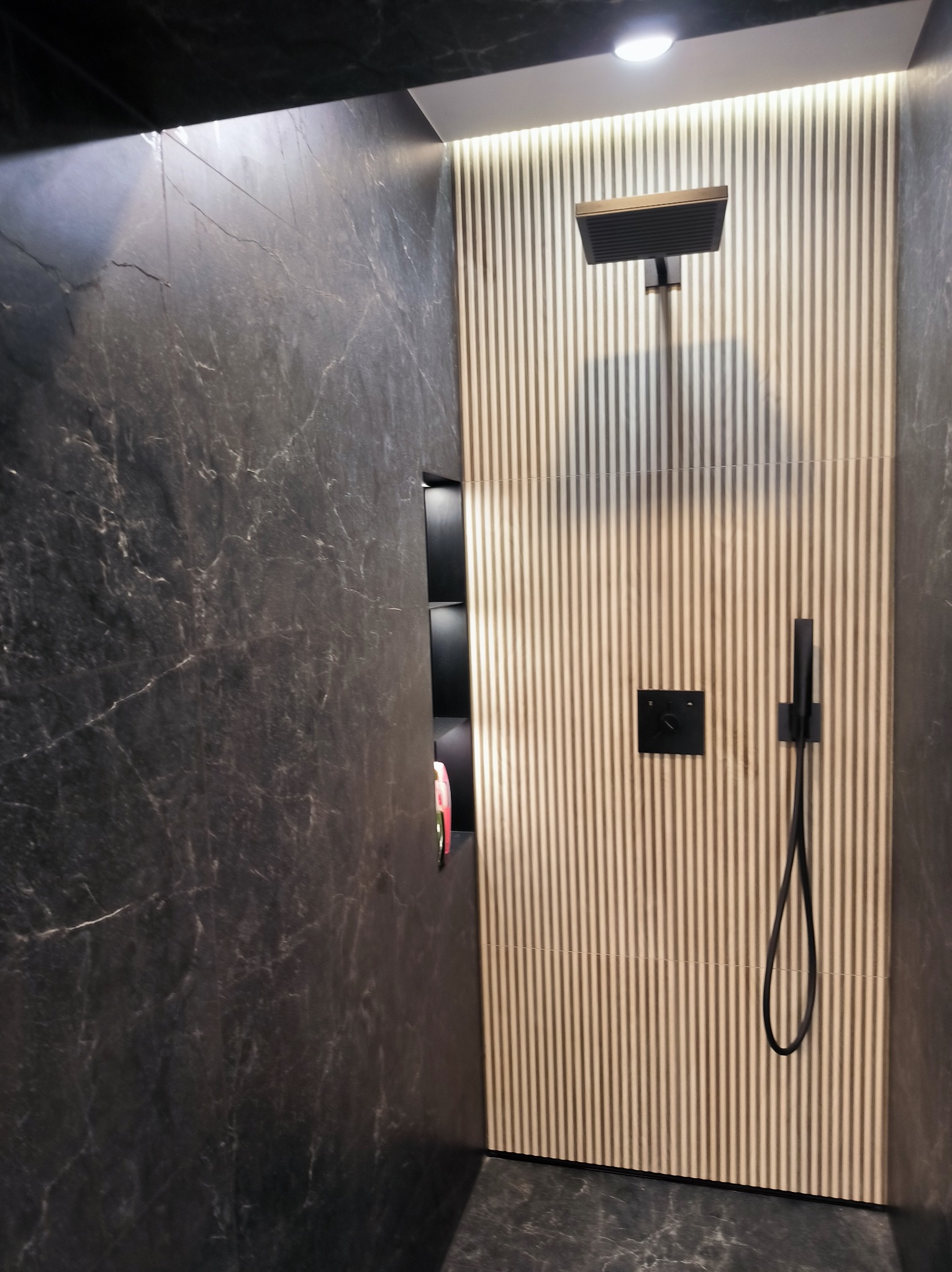 Nowoczesna kabina prysznicowa z deszczownicą i panelami ściennymi w odcieniach beżu i czerni. Minimalistyczny design, eleganckie wykończenie.