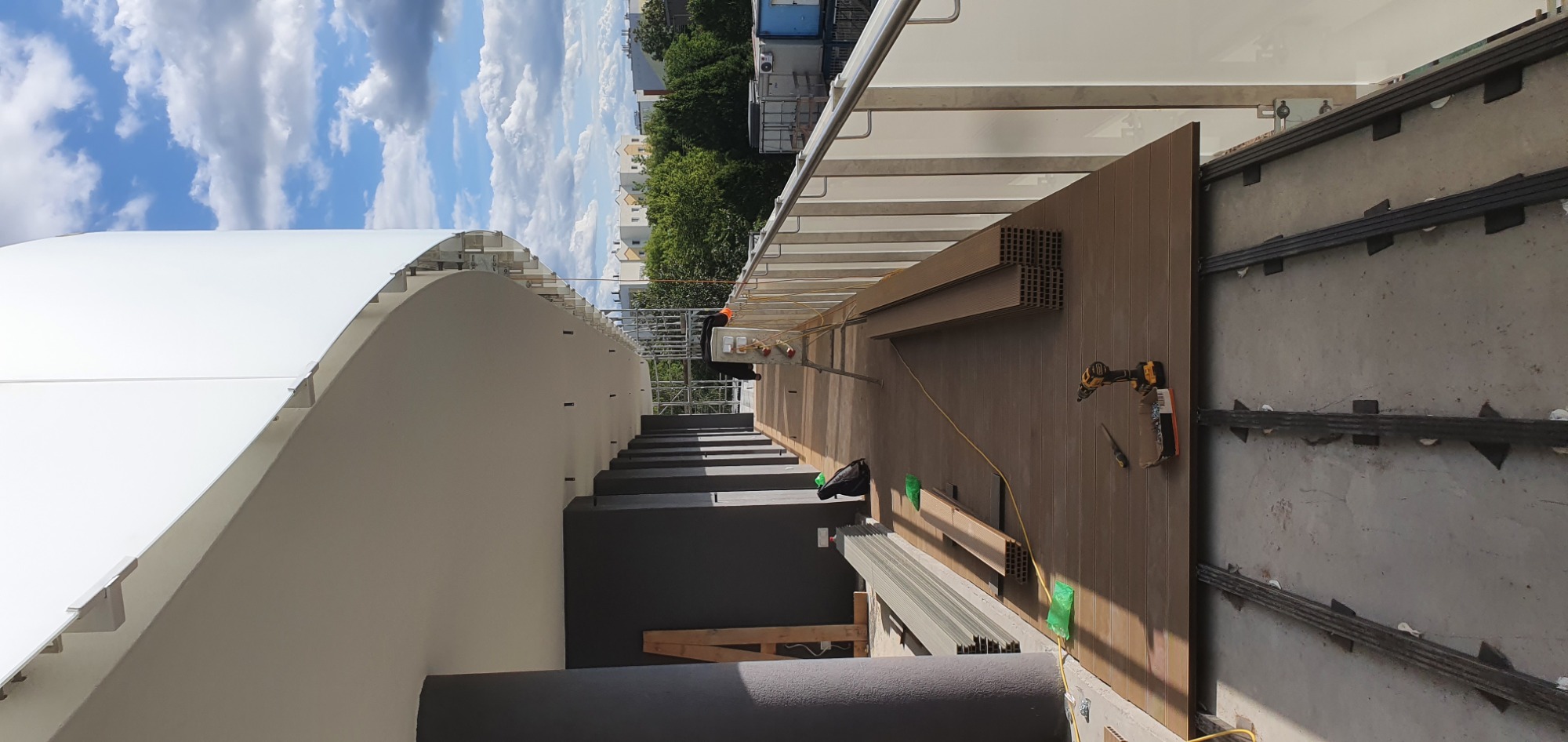 Montaż paneli elewacyjnych kompozytowych na tarasie, widoczne profile montażowe, wkrętarka i elementy wykończeniowe