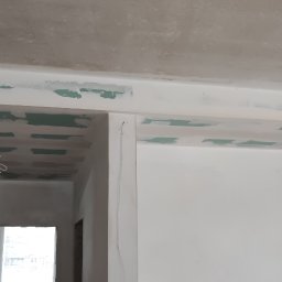 WROT BUD WRÓTNIAK ŁUKASZ Usługi Remontowo Budowlane - Sufit podwieszany z płyt gipsowo-kartonowych, częściowo zaszpachlowany, widoczne łączenia płyt w kolorze zielonym, przygotowanie do dalszych prac wykończeniowych.