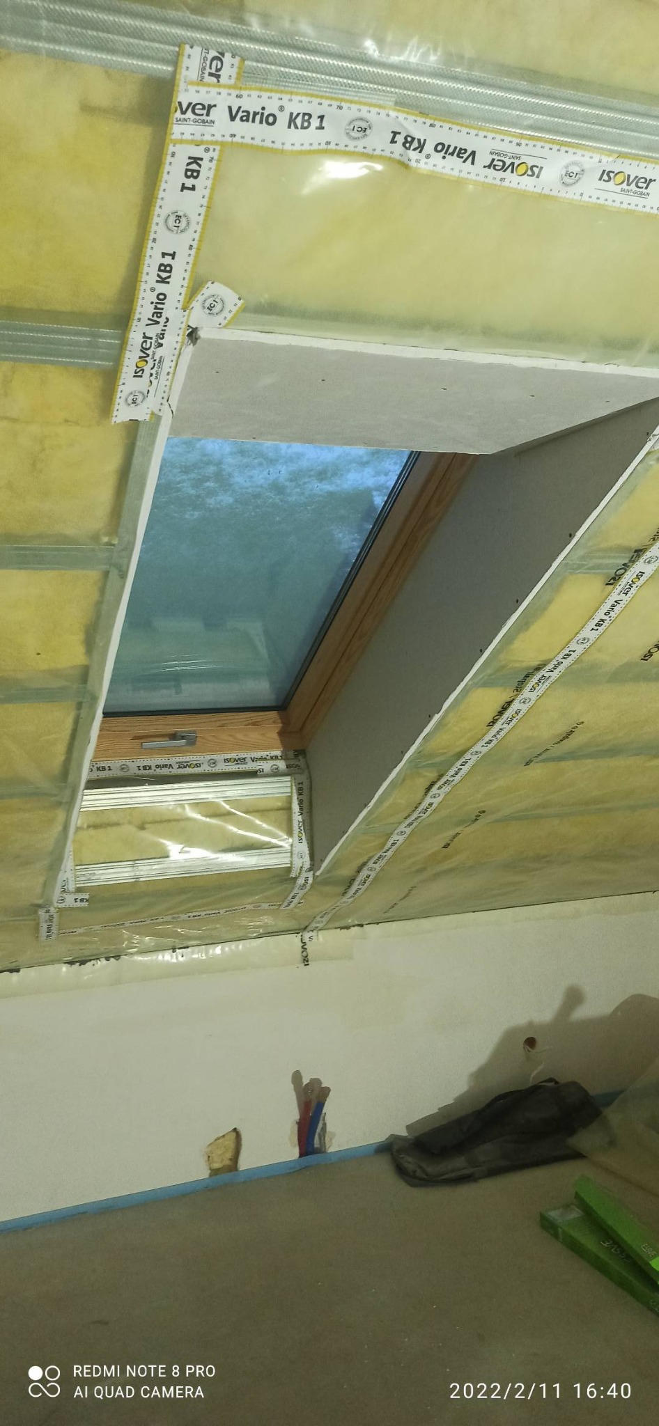 Montaż okna dachowego: widok od wewnątrz na izolację z folią paroizolacyjną Isover Vario KB1, widoczne profile metalowe i fragment płyty gipsowo-kartonowej.