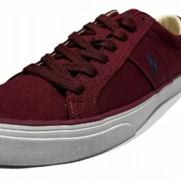 Bordowy, tekstylny but sportowy z granatowym logo jeźdźca na boku, sznurowany, na białej podeszwie.