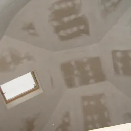 Sufit podwieszany w trakcie szpachlowania, widoczne łączenia płyt gipsowo-kartonowych i okno dachowe z drewnianą ramą