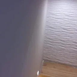 Fragment wnętrza z szarą ścianą, podświetlanymi listwami przypodłogowymi LED, drewnianą podłogą i dekoracyjną ścianą z białymi, falistymi panelami 3D.