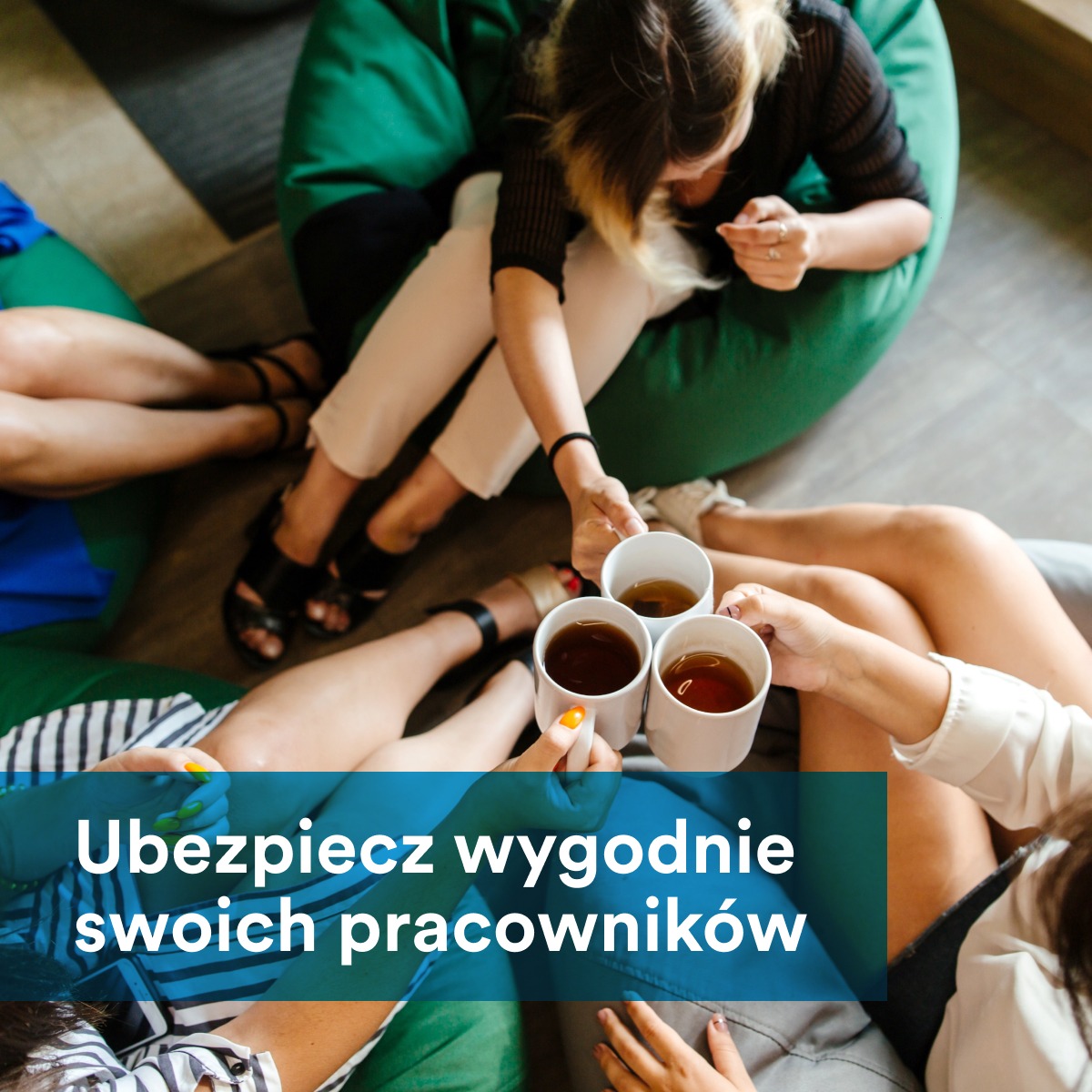 Grupa osób siedzących w kręgu na pufach, trzymających filiżanki z herbatą, widok z góry.