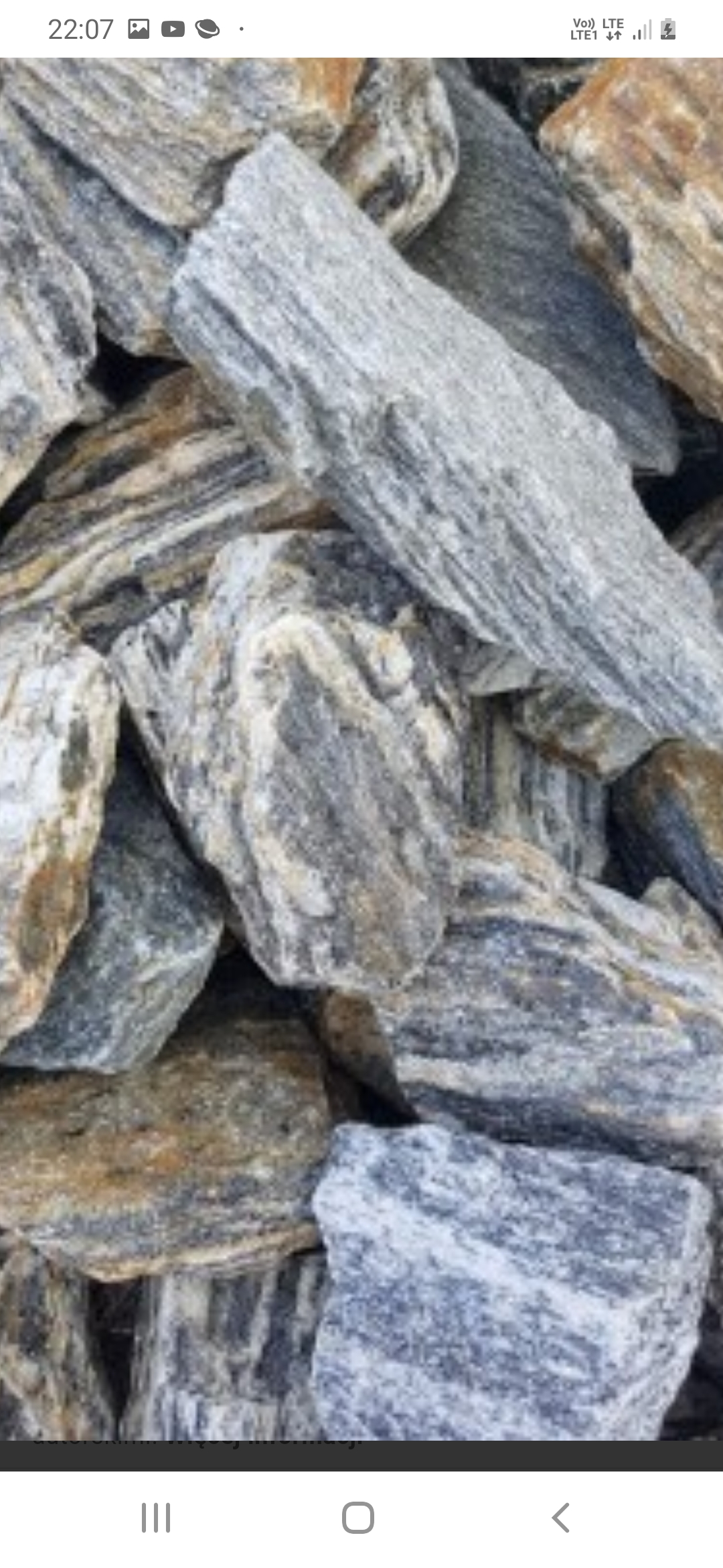 Kupa kamieni o wyraźnych szarych i brązowych pasach, ułożonych jeden na drugim, widoczna tekstura i nieregularne kształty.