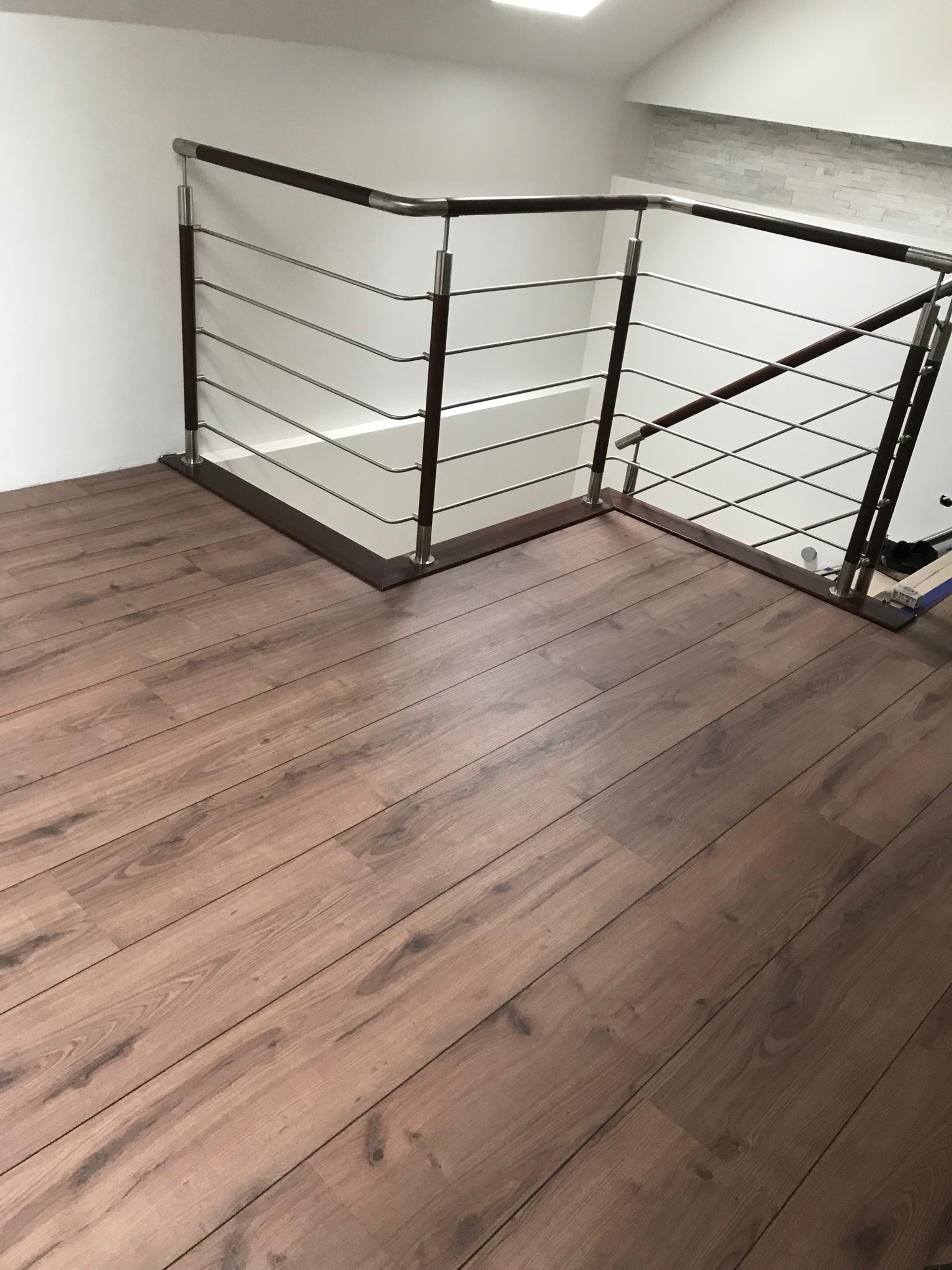 Ułożona podłoga z paneli w odcieniach brązu, widok z góry, przy schodach z balustradą w Łaziskach Górnych.