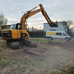 Usługi budowlane Mateusz Schröder - Żółta koparka JCB na placu budowy, obok biały bus z logo firmy budowlanej. Prace ziemne w toku, pochmurne niebo w tle.