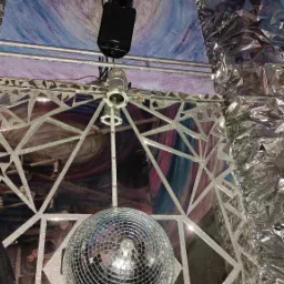 Kula dyskotekowa zawieszona pod sufitem z oświetleniem punktowym i dekoracją z folii aluminiowej, sufit pomalowany w abstrakcyjne wzory.