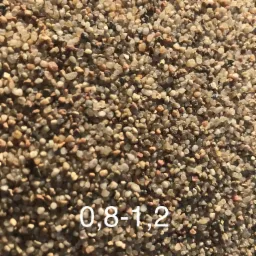 Detale ziaren kruszywa o frakcji 0,8-1,2 mm, w odcieniach beżu i brązu, oświetlone naturalnym światłem.