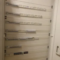 Rozdzielnica elektryczna w białej obudowie, widoczne zabezpieczenia i oznaczenia. Estetyczny montaż wewnątrz szafy.