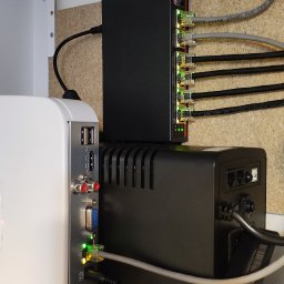 P.H.U TECH-MIKI - Zamontowany switch sieciowy z podłączonymi kablami Ethernet, UPS i router w szafce. Widoczne diody sygnalizujące pracę urządzeń. Estetyczne ułożenie przewodów.