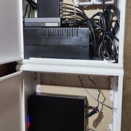 P.H.U TECH-MIKI - Otwarta, biała szafka teletechniczna z zainstalowanymi urządzeniami sieciowymi, kablami i zasilaczami. Widoczne routery, switche i listwy zasilające.
