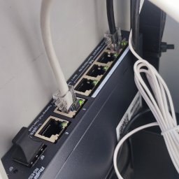 P.H.U TECH-MIKI - Zamknięty switch PoE Ruijie RG-ES206GS-P z podłączonymi kablami Ethernet, wewnątrz obudowy. Widoczne diody sygnalizujące aktywność portów.