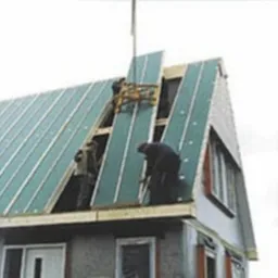 Montaż gotowych elementów izolacji dachu na konstrukcji więźby dachowej z użyciem dźwigu.