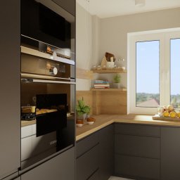EN.concept Jolanta Grzelak - Nowoczesna kuchnia z zabudową w odcieniach szarości, drewnianym blatem i półkami, z widokiem na zewnątrz przez duże okno. Na blacie owoce i zioła w doniczce. Wbudowany piekarnik marki Siemens.