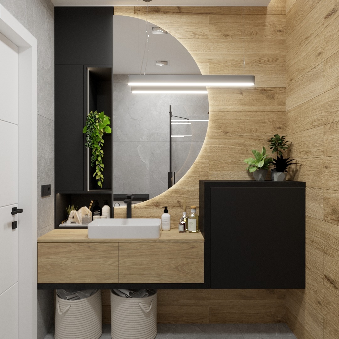 Nowoczesna łazienka z drewnopodobnymi płytkami, okrągłym lustrem z podświetleniem LED, białą umywalką nablatową i czarnymi szafkami wiszącymi, uzupełniona o rośliny doniczkowe i dekoracyjne kosze...