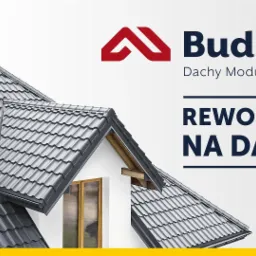 Szary dach modułowy na domu z kominem, logo Budmat i hasło 'Rewolucja na dachu' na jasnym tle.