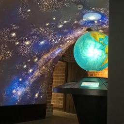 THORIUS Damian Domagalski - Sufit z efektem rozgwieżdżonego nieba, z widocznym globusem i elementami ceglanej ściany w tle, oświetlenie punktowe.