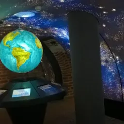 Instalacja sufitu napinanego imitującego rozgwieżdżone niebo w pomieszczeniu z ceglanymi ścianami i podświetlonym modelem Ziemi.