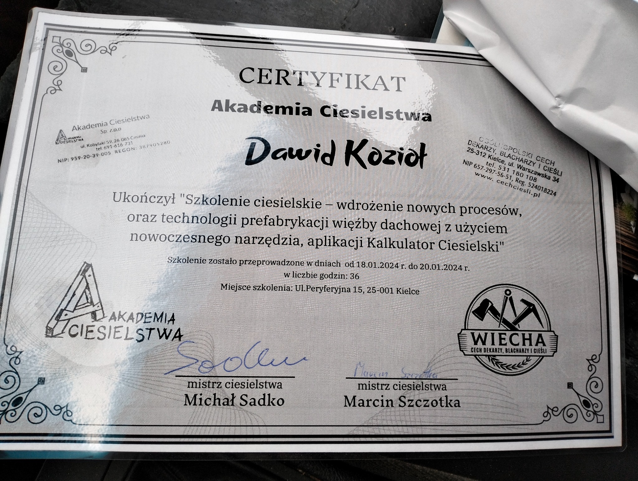 Certyfikat ukończenia szkolenia ciesielskiego przez Dawida Kozioła, wystawiony przez Akademię Ciesielstwa, potwierdzający wdrożenie nowych procesów i technologii prefabrykacji więźby dachowej.
