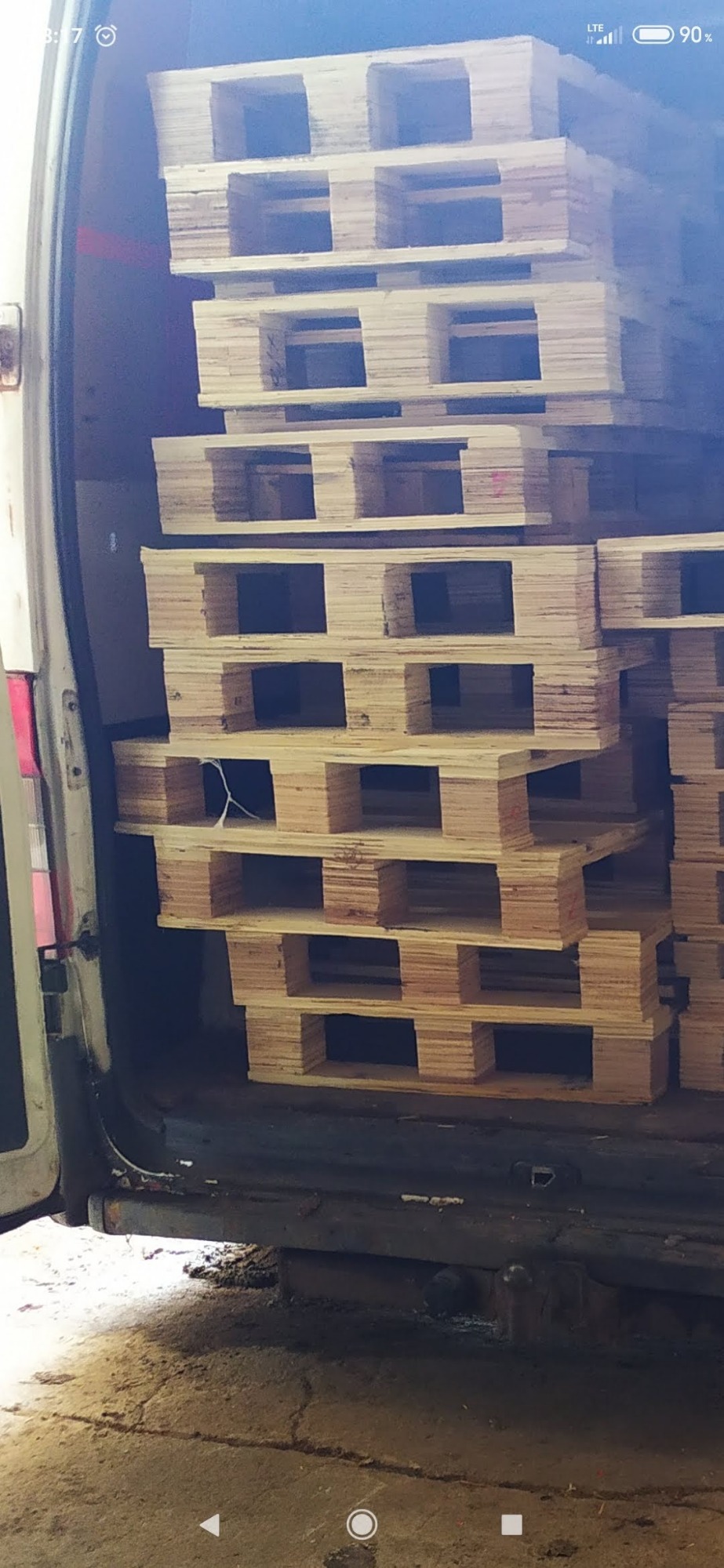 Stos drewnianych palet umieszczonych wewnątrz furgonetki, widoczne detale konstrukcyjne palet i wnętrza pojazdu.