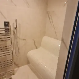 Wykończona sauna z mozaikowym siedziskiem, chromowanym grzejnikiem drabinkowym i deszczownicą, wykończona marmurkowymi płytkami.