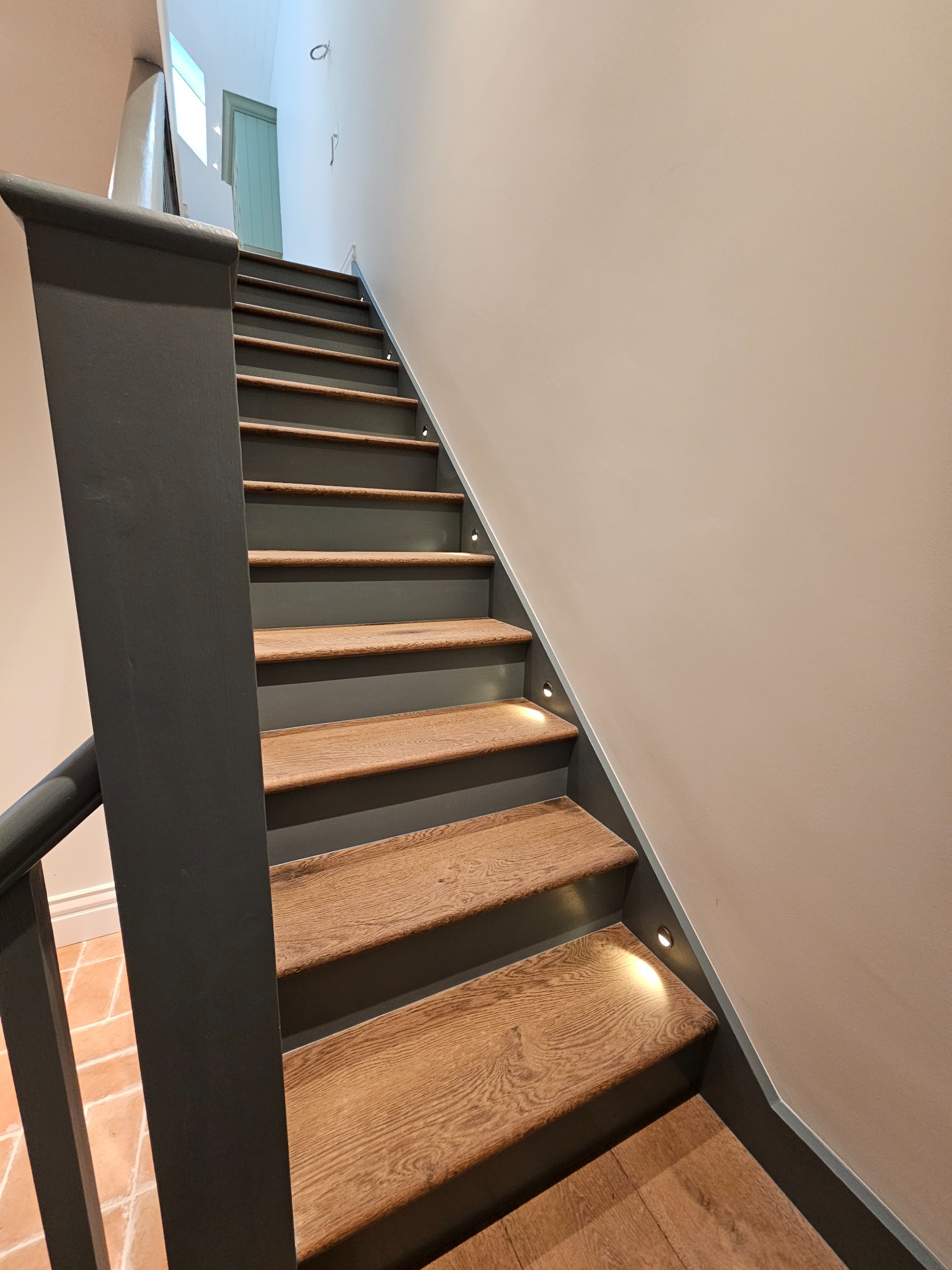 Schody drewniane z podświetleniem LED wzdłuż stopni, szara balustrada, widok z dołu, Nowa Sól.