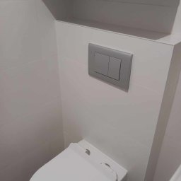 DREWREM USŁUGI REMONTOWO-STOLARSKIE RAFAŁ CHYLA - Nowoczesna łazienka: biała toaleta podwieszana z szarym przyciskiem spłukiwania, białe płytki i szafka wisząca. Minimalistyczny design.