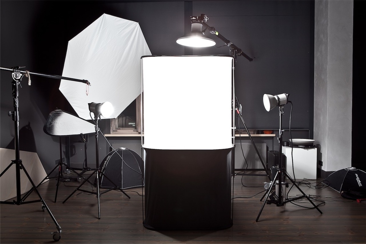 Studio fotograficzne z rozstawionym oświetleniem, softboxami i tłem, gotowe do sesji.