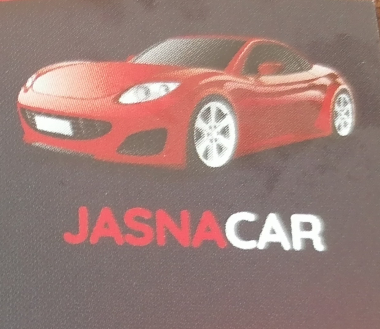 Grafika przedstawia czerwony sportowy samochód nad napisem 'JASNA CAR' na ciemnoszarym tle. Auto ma białe felgi. Napis jest częściowo czerwony, częściowo biały.